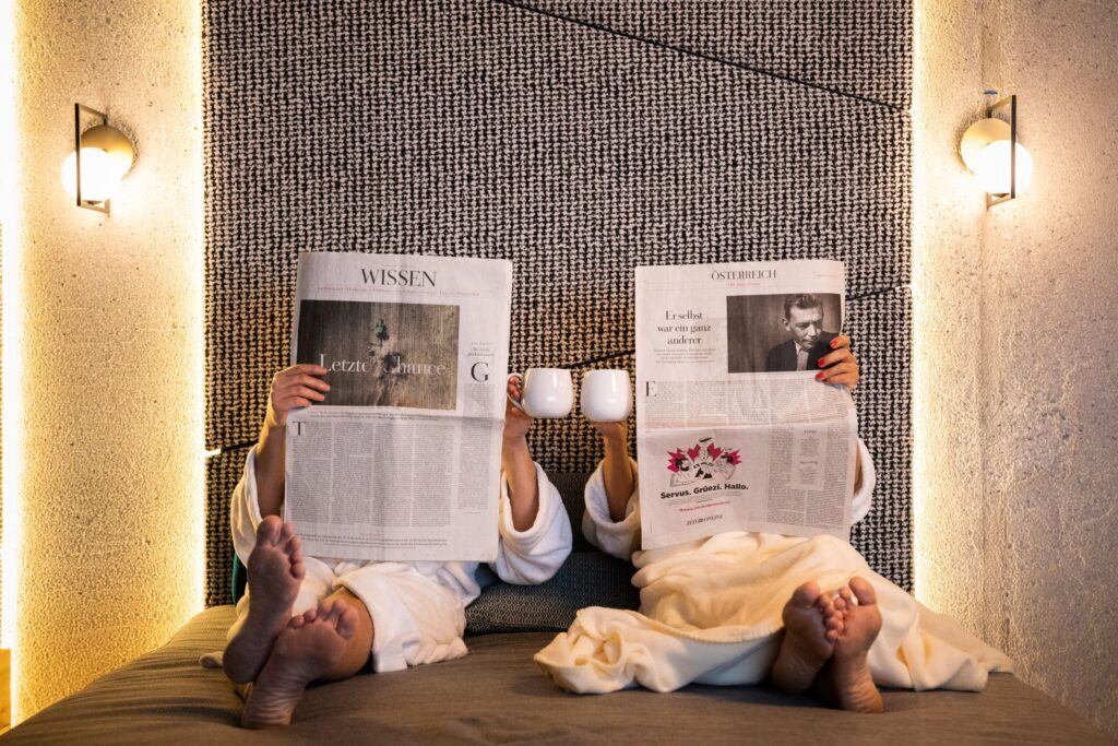 zwei Menschen in Bademanteln lesen Zeitung im SPA Bereich vom Wander- & Wellnesshotel Gassner